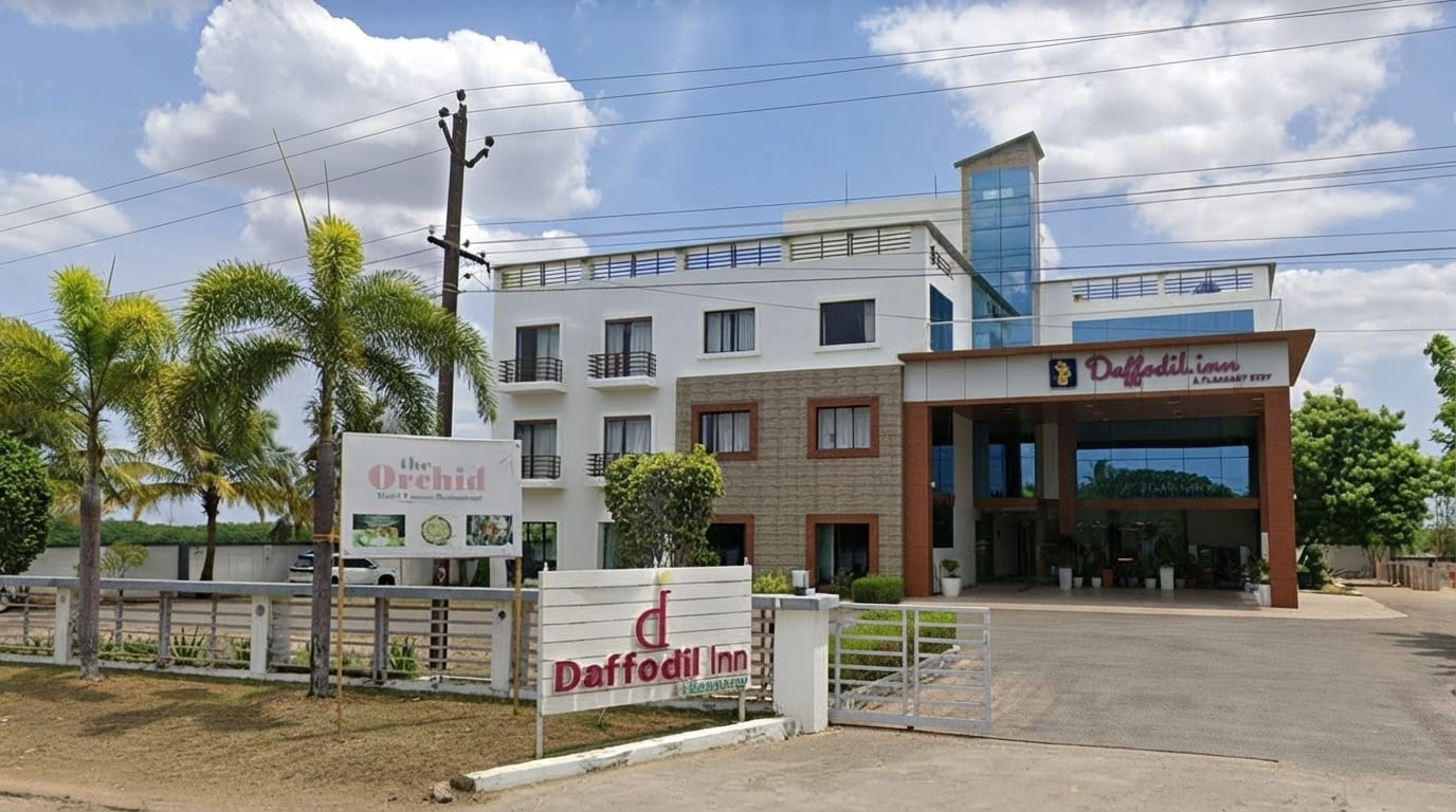 Daffodil Inn exterior with palm trees and The Orchid restaurant entrance in Velankanni