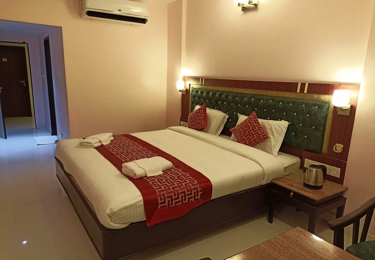 Deluxe guest room with a green tufted headboard, red bed runner, air conditioning and a work desk at Daffodil Inn